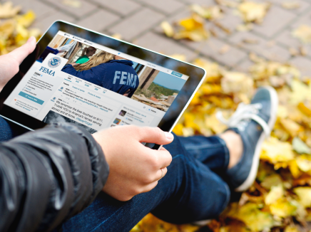 Student holding an ipad with FEMA's twitter account on screen