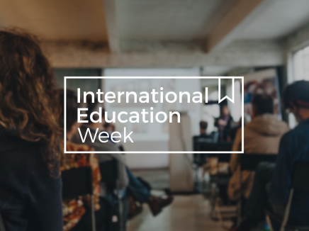 An classroom full of people looking at a projector while an instructor speaks with the words International Education Week across the image