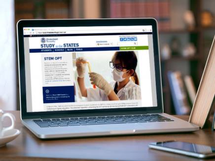 Computer on a desk open with the STEM OPT Hub landing page loaded