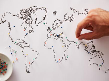 A person adding pins to a world map. 