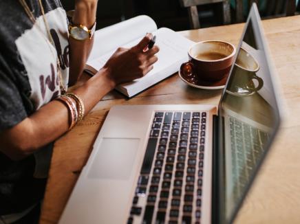 A student using their laptop computer and drinking coffee.