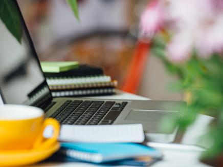 A laptop on a desk with papers around it