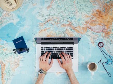 aerial point-of-view of a man typing on a laptop placed on a large world map.