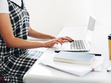 A student sitting at a table working on her laptop