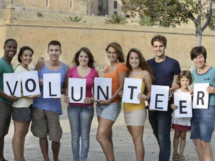 group of young adults holding a volunteer sign