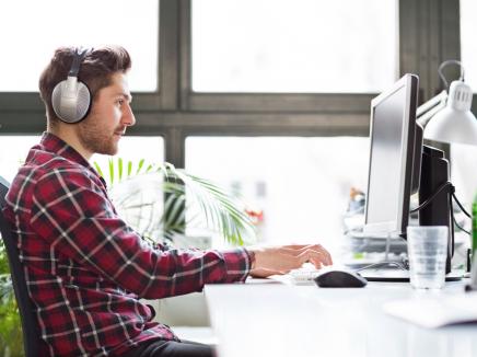 A man with headphones on using his laptop.