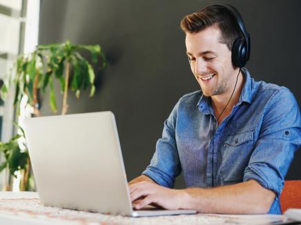 A man listening to headphones on his laptop computer.