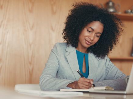 A woman writing on a notepad. 