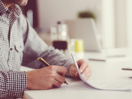 A man signing a document. 