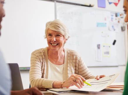 A woman speaking to a man at a woman in a classroom.