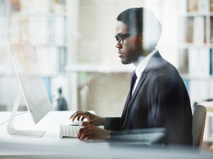 man sitting at a desk, working on his computer