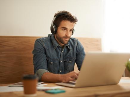 A man working on his computer and wearing headphones.