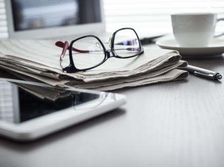 A pair of glasses on top of a stack of paper.