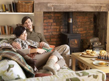 Man and woman sitting on a couch in front of a wood-burning stove