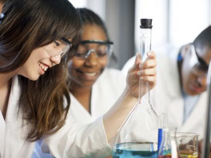 Young student looking at a chemistry beaker. 