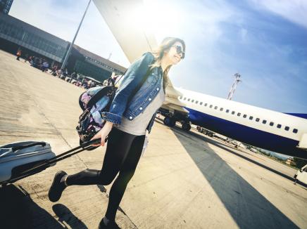A woman with a backpack and roller bag walking to her airplane 