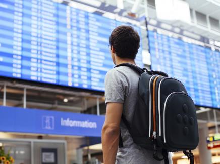 male traveler looking at airport flight schedule