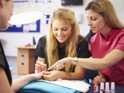 Teacher helping students training to become beauticians. 