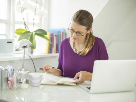 woman sitting at a desk with a laptop open. 