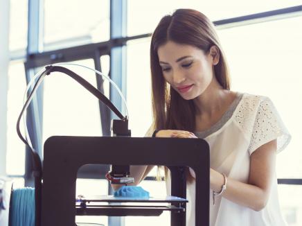 Female student uses a 3D printing machine to print an object