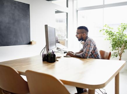 man sitting at clean wooden desk on a computer