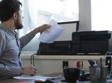 Man sitting at a desk, scanning a piece of paper
