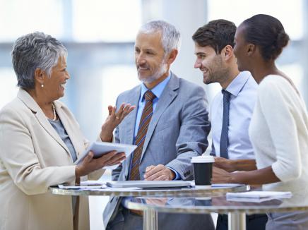 Group of professionals talking around a standing table. 