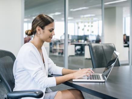 A woman working on her laptop computer in an office.