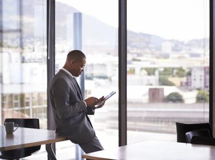 A man looking at a tablet device in a office. 