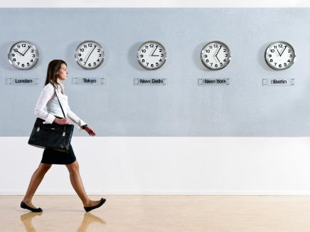 Woman walks down a hall with international clocks. 