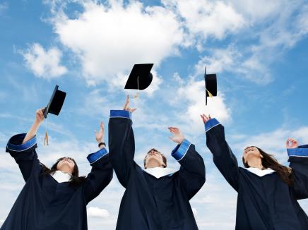 Three graduates throw their caps. 
