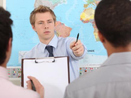Man stands in front of map in classroom. 
